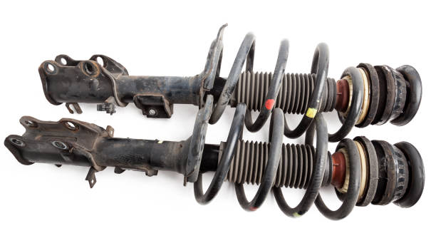 istock Two shock absorber struts with black springs after being used on a car during replacement and repair on a white isolated background. Used spare parts. Auto parts catalog. 1293320910