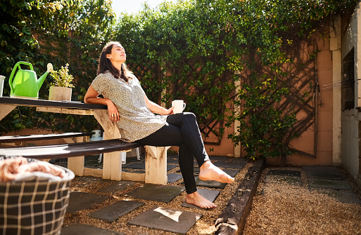Young woman relaxing on bench in backyard of her house