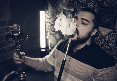 Young man smoking hookah in a bar
