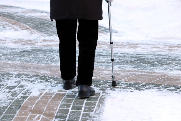 älterer mann mit gehstock auf einer winterstraße - snow walking stock-fotos und bilder
