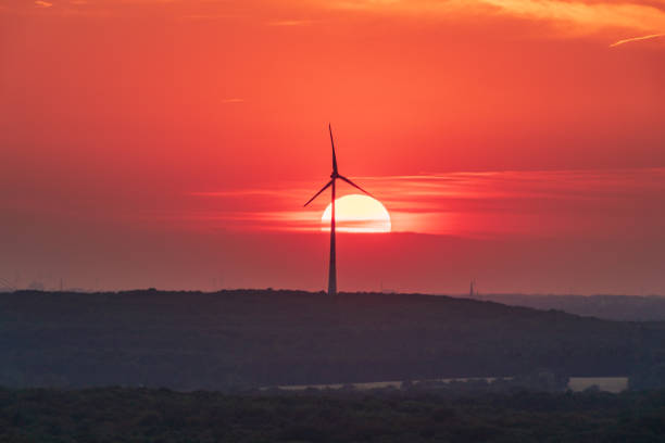 The setting sun and some wind turbines in the Ruhr Area, seen from the Halde Haniel, Bottrop, North Rhine-Westfalia, Germany