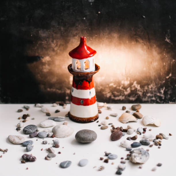 istock A small decorative lighthouse with sea shells and stones on a dark background. Summer, holidays and vacation concept. Flat lay, top view 1293324218
