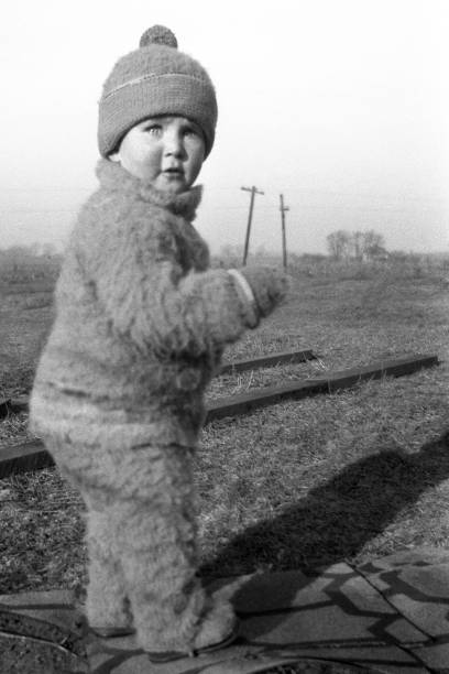 baby boy standing outside on farm in winter 1926 Baby boy dressed in winter clothes playing outdoors on farm in winter of 1926. Wellman, Iowa, USA. 1926 stock pictures, royalty-free photos & images