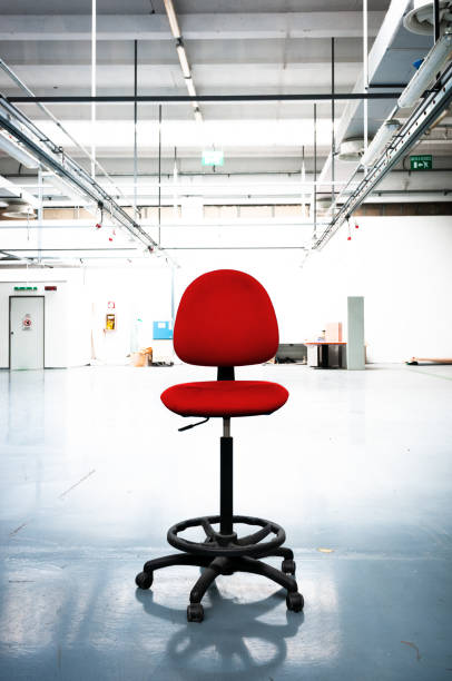 Empty industrial space with an old red office chair in the middle. Toned dimage.