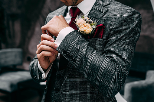 The man straightens his jacket sleeve shirt. The groom straightens his sleeve