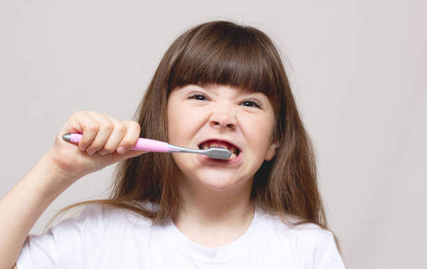 istock A little girl brushing her teeth with a brightly colored toothbrush 1293333951
