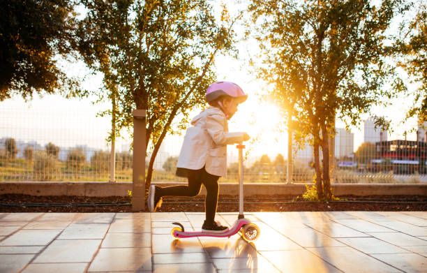 Cute happy girl riding push scooter