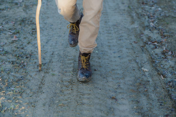 copia el espacio de vista de cuero botas sucias y parte del cuerpo humano caminando en un camino rural fangoso. - bastón de senderismo fotografías e imágenes de stock