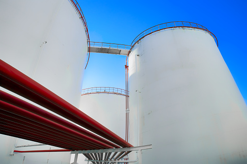 Oil storage tanks in the refinery area and red pipelines