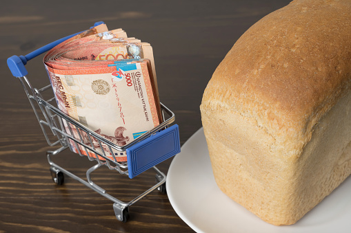 Kazakhstan tenge KZT in a grocery basket with bread. Rising food prices and groceries in Kazakhstan and other countries. Humanitarian assistance.