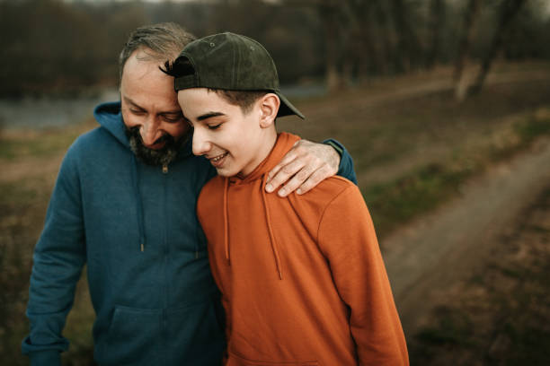 Enjoying some father-son time Mature man and his son walking in the public park father stock pictures, royalty-free photos & images