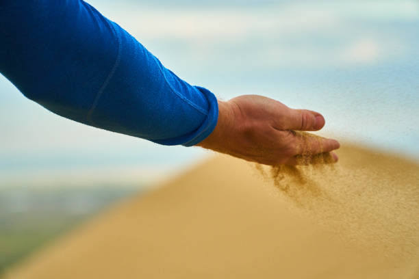 istock Sand falls from your hands. Sand through your fingers. Mountains in desert. 1293348620