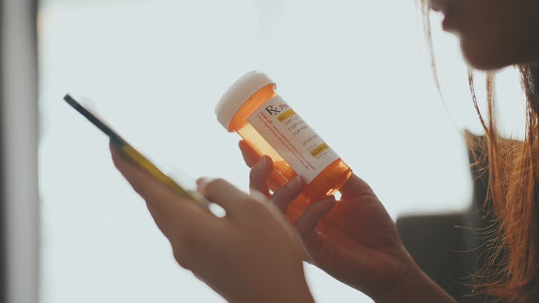 Close-up Hand woman holding pill bottle and using mobile phone