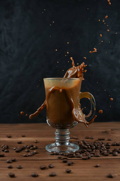istock Splashing of coffee in glass cup on dark background 1293353376