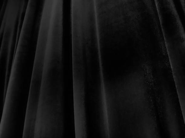 istock Soft waves on black velvet curtains. Stylized defocused image. Dark draperies made of pleasant fabric. Pleats on the curtains. Abstract black and gray background 1293353515