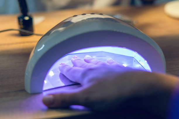 istock Girl dries her nails covered with gel polish using a UV lamp 1293353592