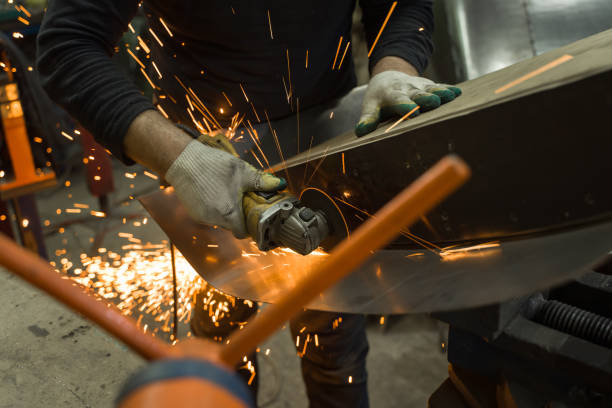 istock Locksmith in special clothes and goggles works in production. Metal processing with angle grinder. Sparks in metalworking 1293357357