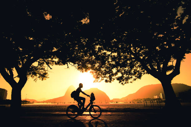 Silhouette of Cyclist in Rio de Janeiro at Sunrise Woman cycling in the morning and the Sugarloaf Mountain is in the horizon, in Rio de Janeiro, Brazil. rio de janeiro stock pictures, royalty-free photos & images