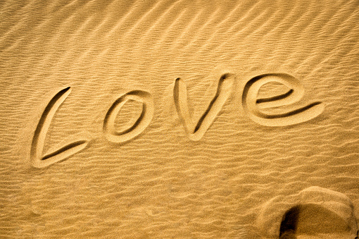 Love hand written text on sand