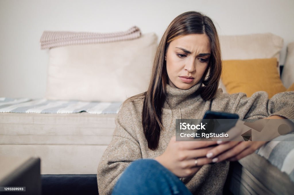 Young woman texting on mobile phone and solving some problems Portrait of a beautiful young woman using a smartphone at home. Online Shopping Stock Photo