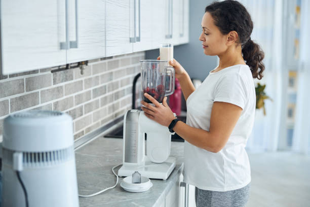 istock Dark-haired female looking at the fruit in the blender 1293363189