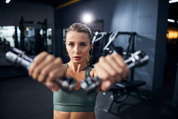 istock Female athlete is performing dumbbell front raises 1293364275