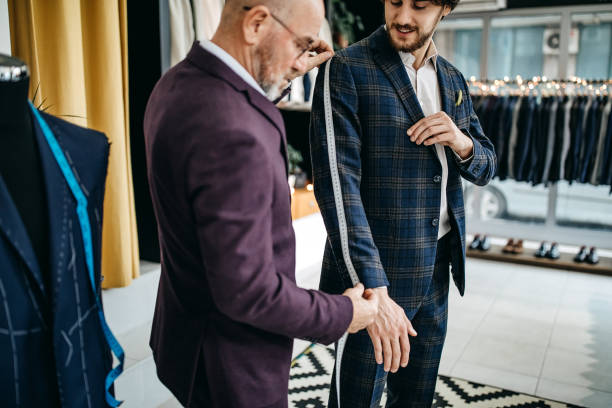 You are tall Senior man measuring length of clients leg for suit in suit store tailor photos stock pictures, royalty-free photos & images
