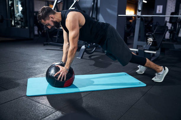 Sportsman doing a plank with medicine ball