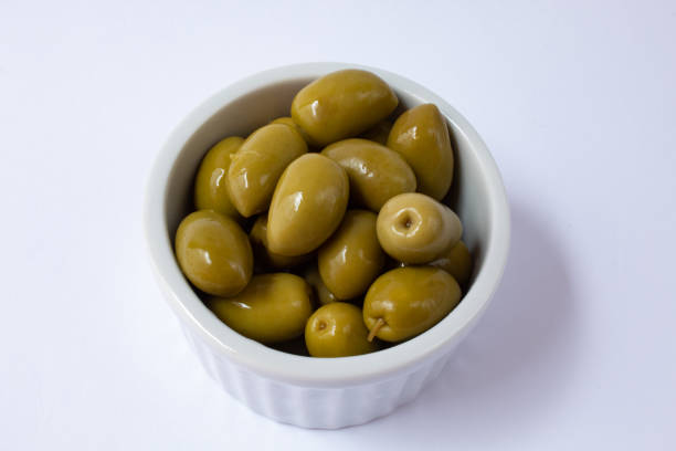 istock Pickled green olives in white bowl on white background 1293369501