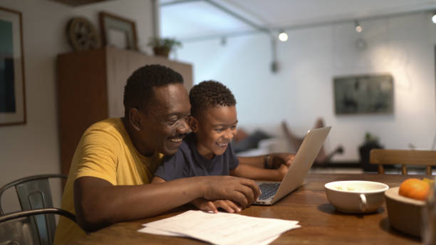 ojciec pomaga synowi studiować w domu - grandparent using computer laptop dining table zdjęcia i obrazy z banku zdjęć
