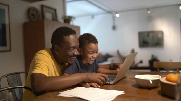 father helping son studying at home - grandparent using computer laptop dining table imagens e fotografias de stock