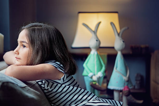 istock Sad little girl is looking trough a window 1293383019