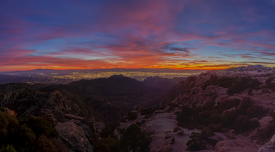 Panorama image of Tucson Arizona as seen from above with the colors of sunset in the distance and mountains.