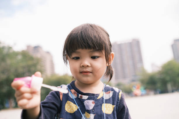 istock Chinese little daughter blowing bubbles in the park 1293388045