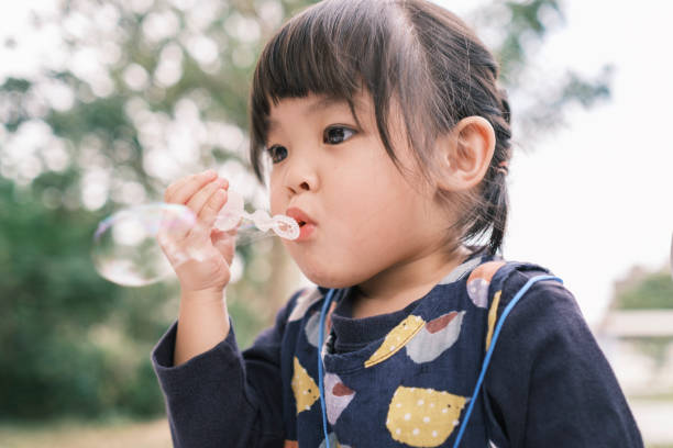 istock Chinese little daughter blowing bubbles in the park 1293388073