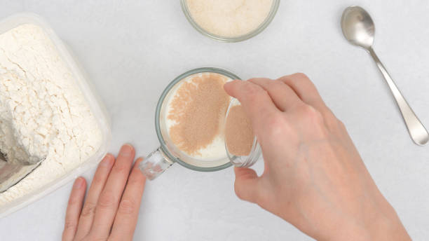 istock Dissolving dry yeast in warm milk. Step by step flat bread recipe, baking process. Close up view from above, woman hands 1293389874
