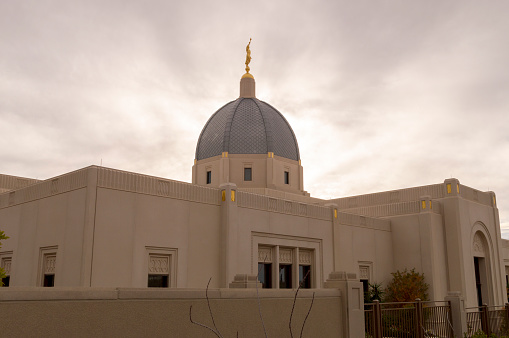 December 24, 2020 - Tucson, Arizona, USA: This is an afternoon view of the exterior of the Tucson Temple, operated by the Church of Jesus Christ of Latter-day Saints.  The central tower and angel Moroni statue are illuminated by a cloud filled sky.