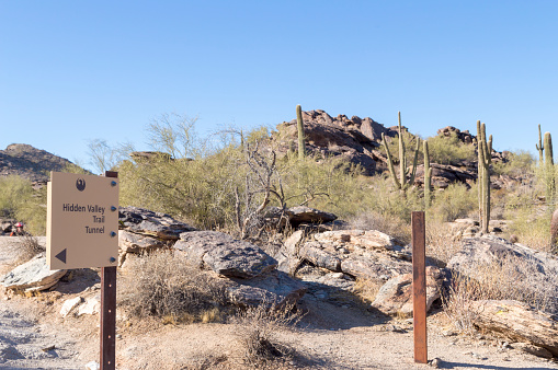 December 20, 2020 - Phoenix, Arizona, USA: A sign points the way toward the Hidden Valley Trail in the desert foothills above Phoenix, Arizona.  Nearby is a natural tunnel formed by falling rocks that can be accessed along the trail.