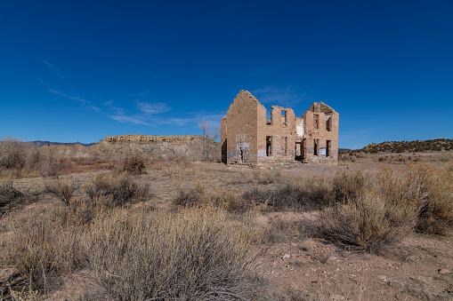 An old structure stands desolately in the arid desert, surrounded by vast stretches of barren land