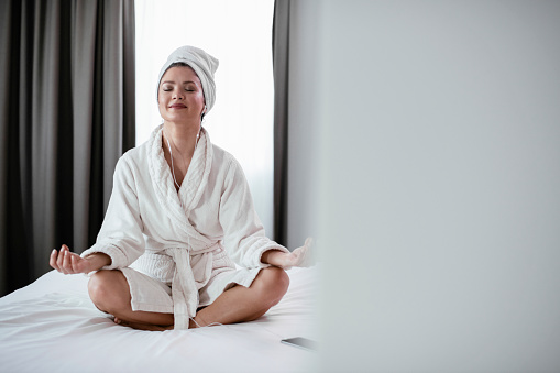 Beautiful woman in bathrobe meditating. Woman enjoying after bathing at home.