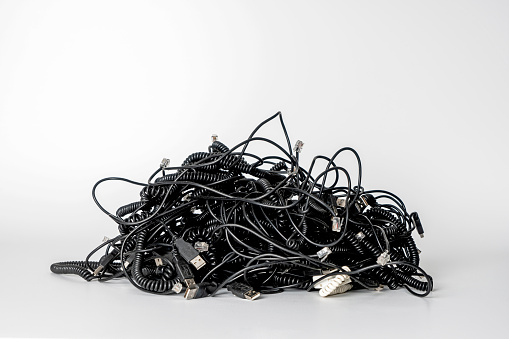 Heap of different computer cables and plugs with a moden digital tablet isolated on white background