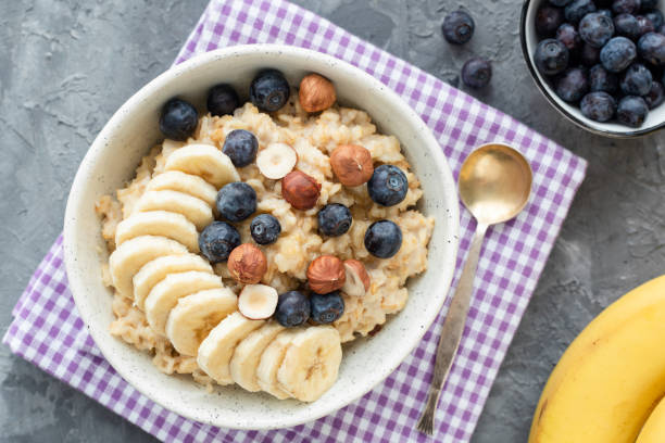 porridge di farina d'avena con mirtillo, banana e nocciola - oatmeal heat bowl breakfast foto e immagini stock