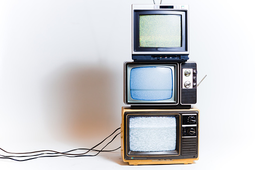 Stack of three retro tvs with static on the screens. Shot on a white background.