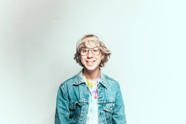 1980s Teen Nerd Guy Studio portraits of a 1980s nerdy guy, shot on a white background and he is wearing an authentic 80s denim jacket and glasses. uncool stock pictures, royalty-free photos & images