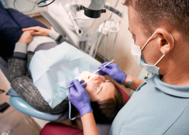 istock Dentist examining woman teeth with diagnostic microscope. 1293408575