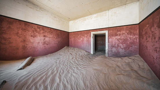 Old Diamond Mining Ghost Town Building Interior Panorama. Nature is coming back. Desert Sand entering old the abandoned german colonial house ín an old deserted Diamond Mine Ghost Town at Kolmanskop, Luderitz, Namibia, Africa.