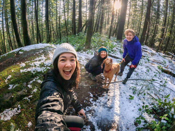 famille multiethnique, amis, chien vizsla posant pour selfie randonnée d’hiver - mt seymour provincial park photos et images de collection