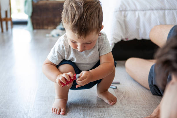 Baby boy playing with toy Baby boy playing with toy on floor in bedroom baby squatting stock pictures, royalty-free photos & images