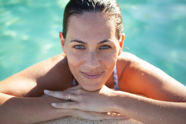 A stock photo of a young woman enjoying the summer weather in a swimming pool with a large inflatable ring.