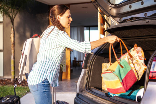 istock Woman loading luggage in car boot 1293417877